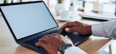 Mãos de um homem mexendo em um notebook, em foto que ilustra artigo sobre governo eletrônico