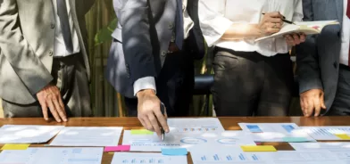 Pessoas discutindo e analisando papeis. O que mudou nos contratos administrativos com a nova lei de licitações