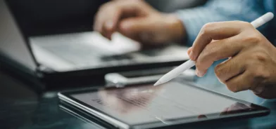 Homem usando tablet e computador. Regulamento de licitações e contratos