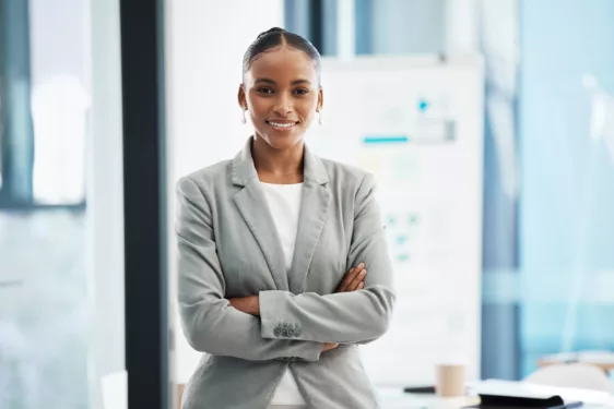 Liderança no setor público, sendo representada por uma mulher de braços cruzados, olhar confiante e sorrindo para a foto