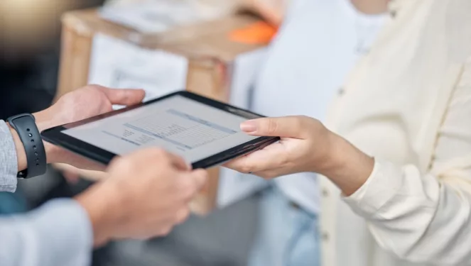 Pessoa entregando tablet à outra, em foto ilustrando importância da avaliação de fornecedores em contratações públicas