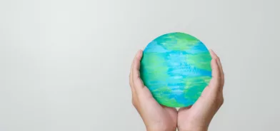 Mãos segurando globo terrestre, ilustrando post sobre responsabilidade socioambiental