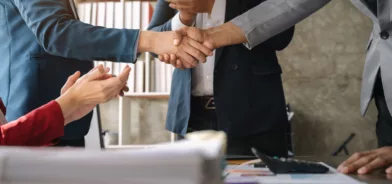 Pessoas apertando as mãos, em foto que ilustra post sobre contratações públicas.