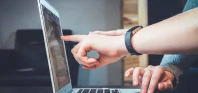 Pessoas usando computador, uma delas aponta para a tela. Foto que ilustra post sobre cidadania digital. Foto: John Schnobrich (@johnschno)/Unsplash