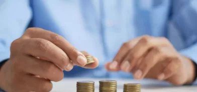 Pessoa mexendo com moedas, em foto que ilustra post sobre contencioso tributário. Foto: Towfiqu barbhuiya/unsplash