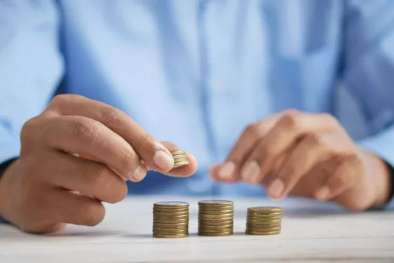 Pessoa mexendo com moedas, em foto que ilustra post sobre contencioso tributário. Foto: Towfiqu barbhuiya/unsplash