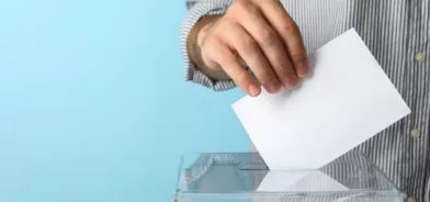 Pessoa colocando cédula dentro de urna, em foto que ilustra post sobre participação cívica.