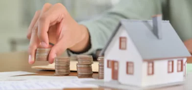 Moedas e maquete de casa, ilustrando post sobre ITBI. Foto: poungsaed_eco/Envato.