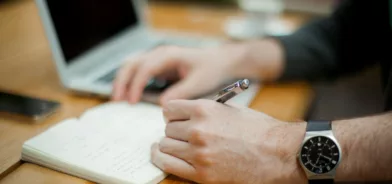 Homem estudando e anotando em caderno, foto que ilustra post sobre princípio da impessoalidade. Reprodução: Alejandro Escamilla/Unsplash.