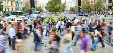 Pessoas atravessando a rua em Santiago, no Chile. Foto que ilustra post sobre coesão social. Reprodução: Mauro mora/Unsplash.