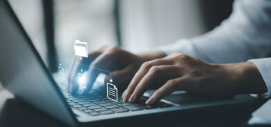 Empresário digitando em um teclado com hologramas de arquivos de documentos digitais, em foto que ilustra post sobre sistema de gestão de documentos. Reprodução: dekddui1405/Envato.