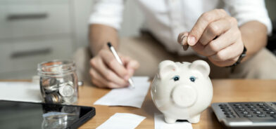 Homem colocando moeda de dinheiro no cofrinho para economizar dinheiro. Foto que ilustra post sobre controle de gastos públicos. Reprodução: coolhand1180/Envato.