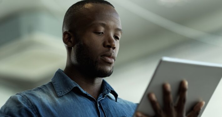 Homem segurando e interagindo com um tablet, em foto que ilustra post sobre PDTIC. Reprodução: YuriArcursPeopleimages/Envato.