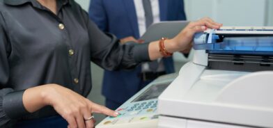 Assistente de escritório usando impressora, em foto que ilustra post sobre rotinas administrativas. Reprodução: DragonImage/Envato.