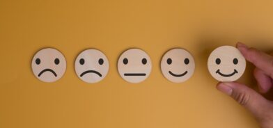 Uma mão escolhe um rosto sorridente entre uma sequência de expressões faciais, em foto que ilustra post sobre confiança institucional. Reprodução: donut3771/Envato.