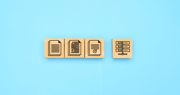 Uma imagem minimalista com blocos de madeira exibindo ícones que representam documentos e servidores, ilustrando post sobre sistema de protocolo. Foto: 1footage/Envato.
