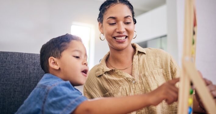 Criança com professora ajudando em lição escolar, foto que ilustra post sobre educação inclusiva. Reprodução YuriArcursPeopleimages/Envato.