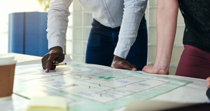 Pessoas discutindo juntos na mesa em um escritório, em foto que ilustra post sobre capacidade de resposta. Reprodução: FlamingoImages/Envato.