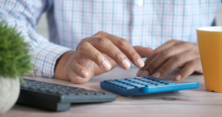 Homem usando calculadora, em foto que ilustra post sobre Imposto de Renda. Reprodução: Towfiqu barbhuiya/Envato.