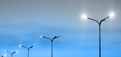 Paisagem urbana, luz de rua iluminada, lanternas modernas e céu azul vibrante. Foto que ilustra post sobre iluminação pública. Reprodução: blazhulia/Envato.