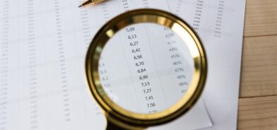 Lupa em relatório financeiro. Foto que ilustra post sobre Lei da Transparência Fiscal. Reprodução: FabrikaPhoto/Envato.