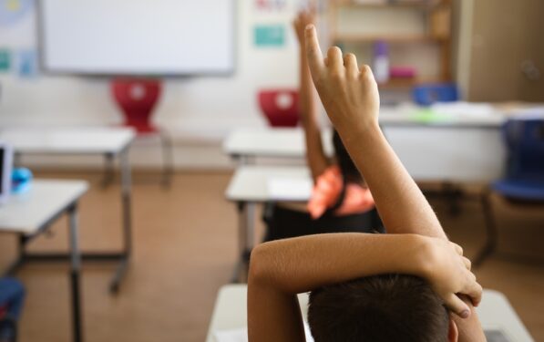 Aluno com mão levantada, em post sobre quais são os principais desafios da educação infantil. Reprodução: Wavebreakmedia/Envato.