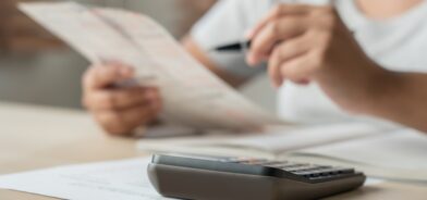 Mulher usando calculadora e anotações, em foto que ilustra post sobre taxa de expediente. Reprodução: stockerthings/Envato.