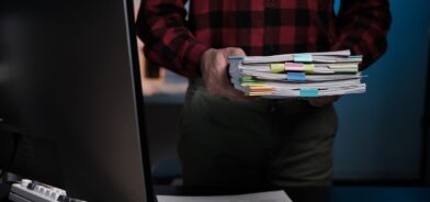 Homem segurando pilha de arquivos, em foto que ilustra post sobre descrição arquivística. Reprodução: paegagz/Envato.