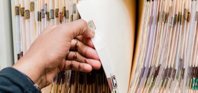 Pessoa manuseando documentos físicos, em foto que ilustra post sobre preservação de documentos. Reprodução: rohaneh/Envato.