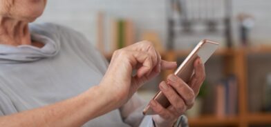 Mulher idosa usando smartphone, em foto que ilustra post sobre assistente virtual inteligente. Reprodução: DragonImages/Envato.