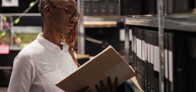 Mulher analisando arquivo, em foto que ilustra post sobre manual de gestão de documentos. Reprodução: DC_Studio/Envato.