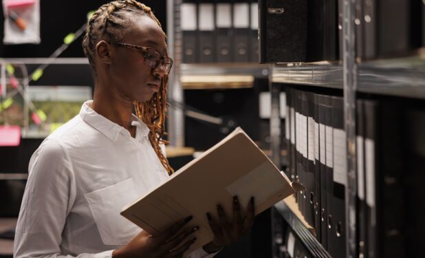 Mulher analisando arquivo, em foto que ilustra post sobre manual de gestão de documentos. Reprodução: DC_Studio/Envato.