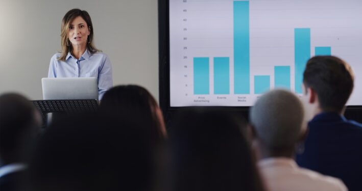 Mulher fazendo uma apresentação analisando gráficos. Foto que ilustra post sobre agenda regulatória. Reprodução: YuriArcursPeopleimages/Envato.