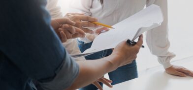 Pessoas discutindo documento, em foto que ilustra post sobre avaliação de políticas públicas. Reprodução: wichayada69/Envato.