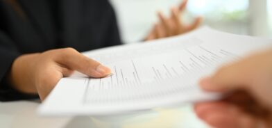 Pessoa entregando um documento para outra. Foto que ilustra post sobre falsificação de documento público. Reprodução: prathanchorruangsak/Envato.