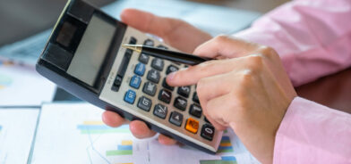 Pessoa fazendo contas em calculadora. Foto que ilustra post sobre execução orçamentária. Reprodução: Lucky7Trader/Envato.
