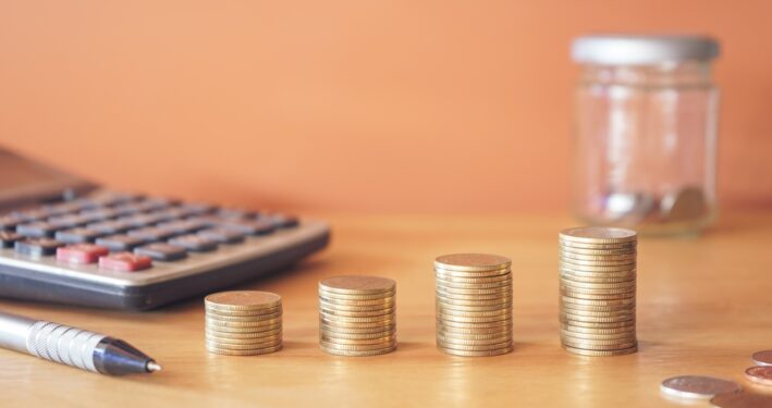 Moedas e calculadora. Foto que ilustra post sobre empenho orçamentário. Reprodução: tendo23/Envato.