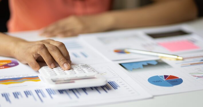 Pessoa fazendo contas em calculadora, em foto que ilustra post sobre lei Complementar 226/2026 (Lei do Descongela). Reprodução: wasant1/Envato.