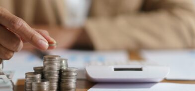 Mulher contando moedas e calculando. Foto que ilustra post sobre transferências constitucionais. Reprodução: indypendenz/Envato.