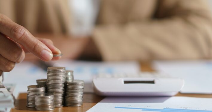 Mulher contando moedas e calculando. Foto que ilustra post sobre transferências constitucionais. Reprodução: indypendenz/Envato.