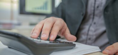 Homem fazendo contas em calculadora. Foto que ilustra post sobre duodécimo municipal. Reprodução: wirestock/Envato.