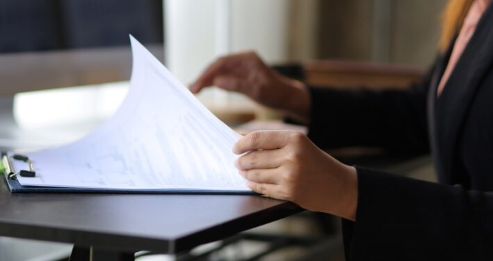 Mulher analisando documento e produzindo Estudo Técnico Preliminar (ETP). Reprodução: wasant1/Envato.
