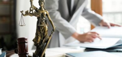 Pessoa avaliando leis, com estátua da justiça em primeiro plano. Foto que ilustra post sobre legislação orçamentária. Reprodução: ijeab/Envato.
