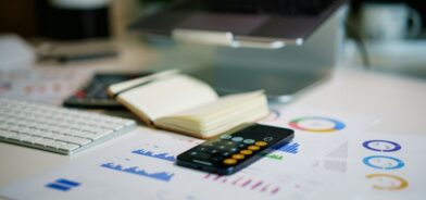 Calculadora, anotações e contas. Foto que ilustra post sobre previsão orçamentária. Reprodução: Jakub Żerdzicki/Envato.
