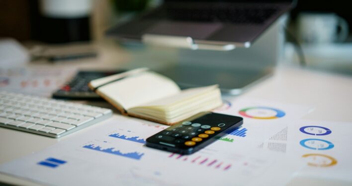 Calculadora, anotações e contas. Foto que ilustra post sobre previsão orçamentária. Reprodução: Jakub Żerdzicki/Envato.