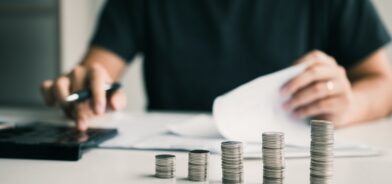 Homem fazendo contas em calculadora. Foto que ilustra post sobre princípios orçamentários. Reprodução: wutzkoh/Envato.