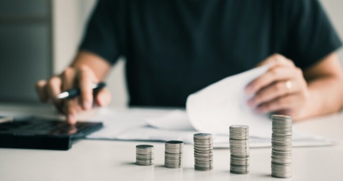 Homem fazendo contas em calculadora. Foto que ilustra post sobre princípios orçamentários. Reprodução: wutzkoh/Envato.