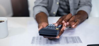 Homem fazendo contas em calculadora. Foto que ilustra post sobre balanço orçamentário. Reprodução: Wavebreakmedia/Envato.