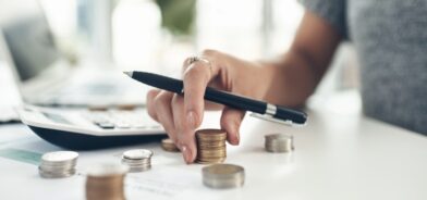 Foto aproximada de uma pessoa calculando finanças em um escritório. Ilustra post sobre caudas orçamentárias. Reprodução: YuriArcursPeopleimages/Envato.