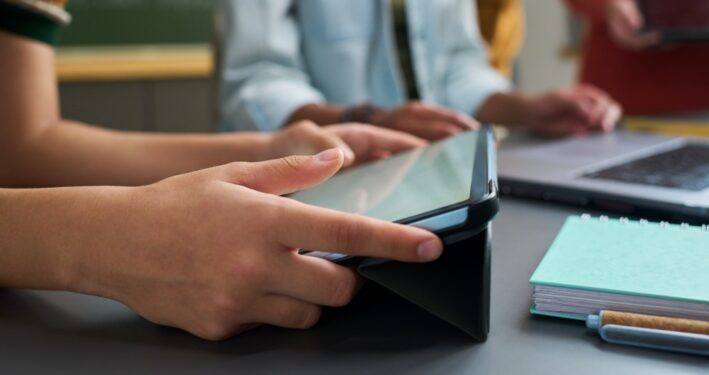 Adolescentes estudando com auxílio de tablets e computador. Foto que ilustra post sobre Política Nacional de Educação Digital. Reprodução: Pressmaster/Envato.